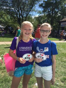 Girls holding "I heart Natick" signs at Natick Days