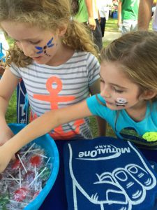 Girls taking candy from MutualOneBank booth at Natick Days