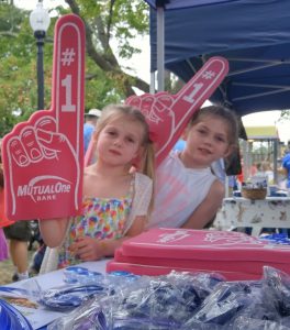 Young girls wearing foam fingers at MutualOne Bank's booth at Natick Days