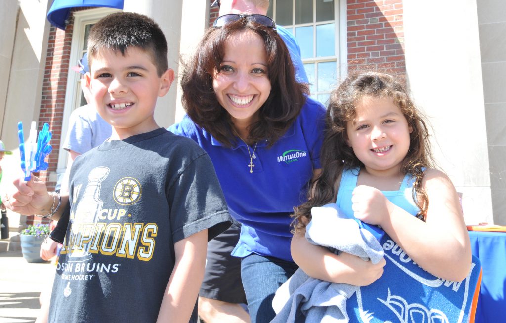 MutualOne Bank employee posing with children holding giveaways