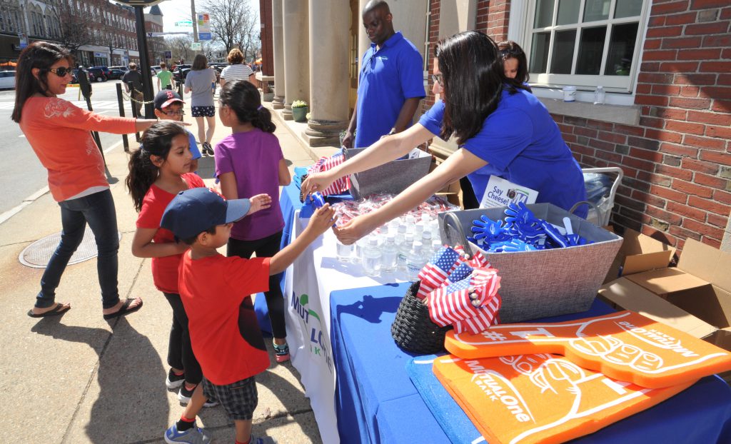 MutualOne Bank employee handing noise makers to children