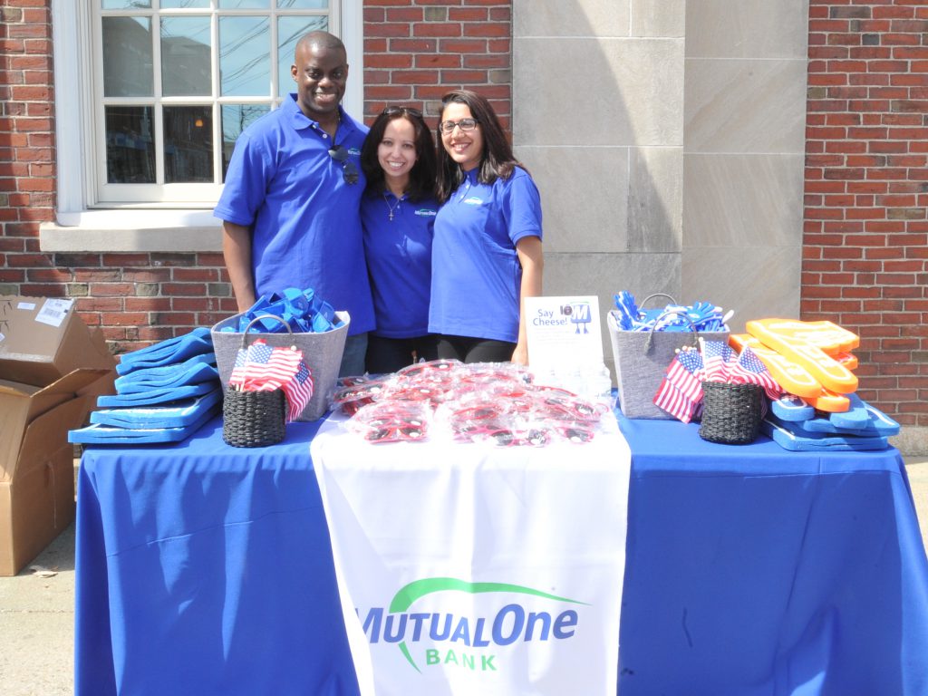 MutualOne Bank Employees posing behind giveaway table