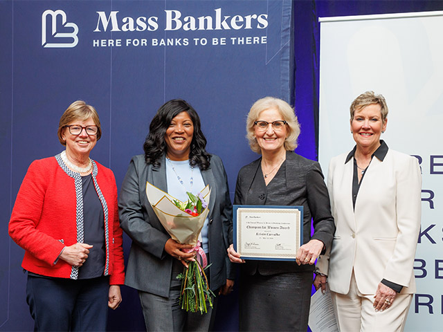 Group photo of 4 people holding an award and a bouquet of flowers.