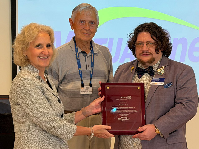 A photo of three people holding up an award.